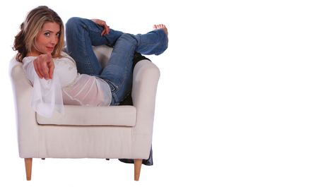 isolated beautiful blonde girl relaxing on sofa and point her finger at youの写真素材