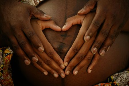 horizontal or landscape shot of african american couple hands shaping heart covering the wife's pregnant bellyの写真素材