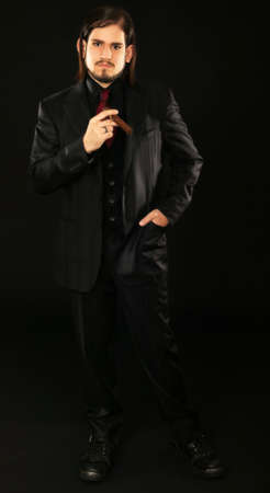 man in high fashion suit holding up a cigar. shot againts black background