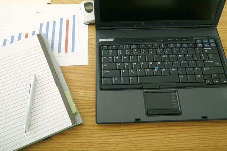 shot taken from top showing laptop on table and some empty notepad with pen