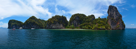 The island of Thailand overgrown with greenery in the blue sea against the sky with cloudsの写真素材