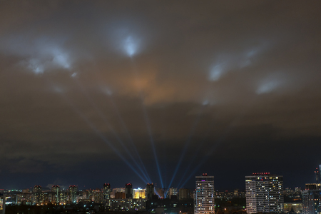 searchlights shine in the night sky over the cityの写真素材