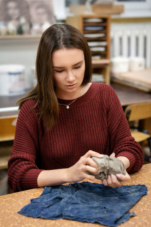 The girl sculpts a mug from clay close up.の写真素材