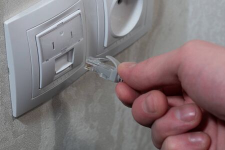 A male hand inserts an internet cable into network connection plug.