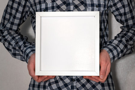 Male hands hold an empty white frame.
