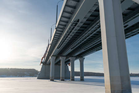 Bridge bottom view in winter. Metal structures and columns against the sky.