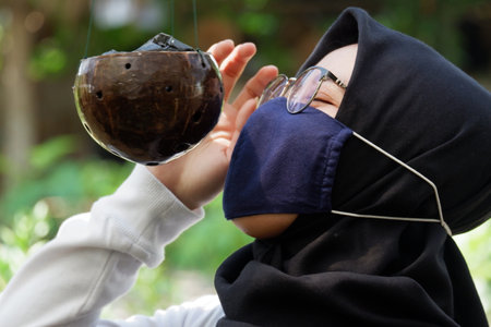 Beautiful female tourists who wear hijab visiting flower gardens during the pandemic wear masks to comply with health and safety protocols from COVID-19 : Yogyakarta, Indonesia : June 3, 2020の写真素材