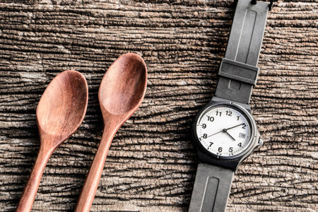 watch and wooden spoon on tableの写真素材