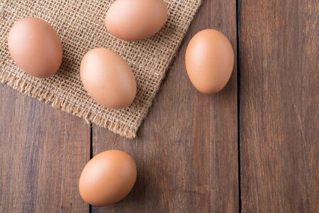 Raw eggs on sackcloth on wooden table, top view
