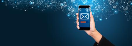 Email marketing and newsletter concept. Sending a message on smartphone screen in businesswoman hand.の写真素材