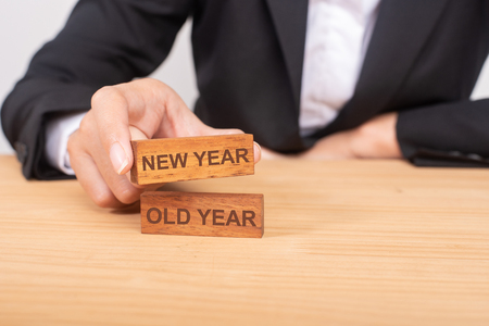 Hand of businesswoman choosing wood blog with icon and word New Year and Old Year.の写真素材