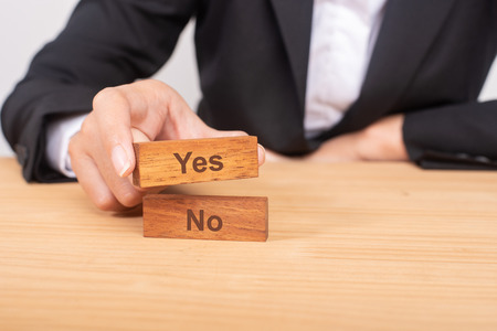 Hand of businesswoman choosing wood blog with icon and word Yes and No.の写真素材