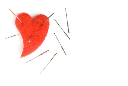 Red heart and the sewing needles, is isolated on a white background