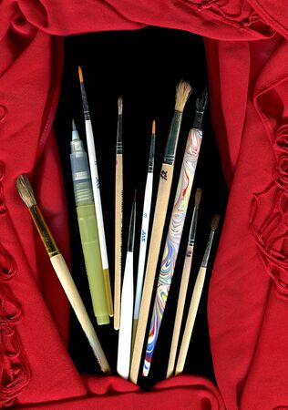 A lot of brushes and red scarf on a black backroundの写真素材