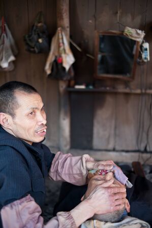 CHENGDU,CHINA-APRIL 24, 2011:unknown disability barber Barber for the guests, locals like to go here for a haircut, we are willing to help him, April 24, 2011のeditorial素材