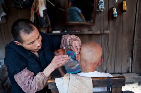 CHENGDU,CHINA-APRIL 24, 2011:unknown disability barber Barber for the guests, locals like to go here for a haircut, we are willing to help him, April 24, 2011のeditorial素材