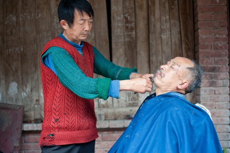 SICHUAN,CHINA-APRIL 4,2010ï¼Nameless barber working local farmers lost their land, in order to survive, diverted business, Sichuan, China, April 4, 2010のeditorial素材