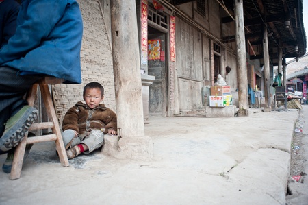SICHUAN,CHINA-APRIL 4,2010ï¼Unnamed small boy sitting on the floor playing, his parents are working in the field, upbringing by his grandfather, Sichuan, China, April 4, 2010のeditorial素材