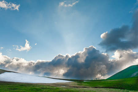 Summer landscape with green grass, mountains and cloudsの写真素材