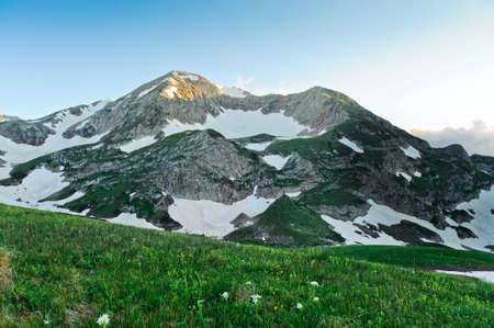 Summer landscape with green grass, mountains and cloudsの写真素材