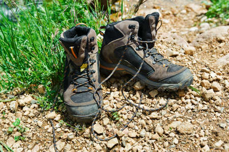 Walking boots in front of a mountain stream in a forest landscape