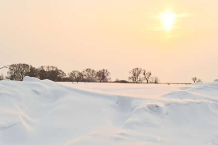 the photo shows a snowy field at sunriseの写真素材