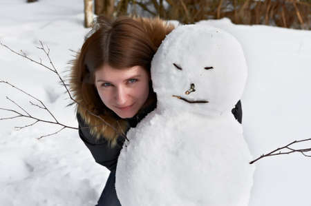 attractive girl standing beside a snowmanの写真素材