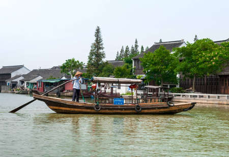 ZHOUZHUANG-AUGUST 19: Chinese gondolier sailing on a boat in the village on the water, on August 19,2012, Zhouzhuang, Chinaのeditorial素材