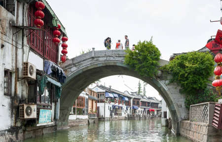 ZHOUZHUANG-AUGUST 19: Tourists walk on the bridge in the village on the water , on August 19,2012, Zhouzhuang, Chinaのeditorial素材