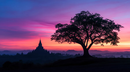 A tranquil sunset scene depicting a silhouetted tree in the foreground with an ancient temple in the background, capturing the essence of serenity and beauty.の素材