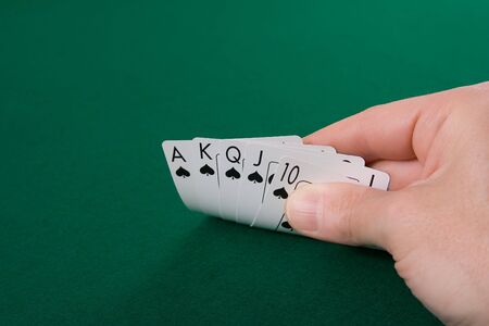 Hand lifting up playing cards at a poker game tableの写真素材