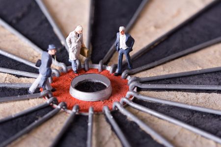 Three miniature businessman walking to the center of a dartboard. Shallow depth of field.の写真素材