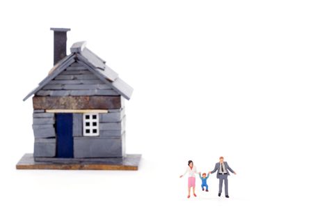 Rustic miniature house with a young couple and a child over white background. Shallow depth of field.の写真素材