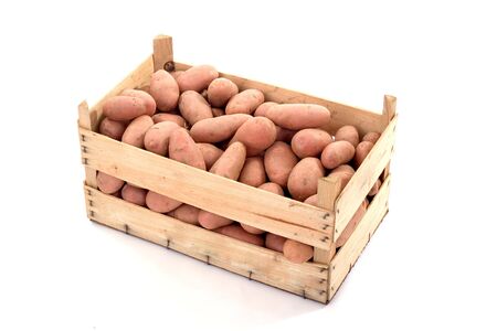 Potatoes inside a wood box isolated over white backgroundの写真素材