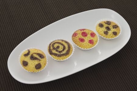 Four small cakes on a plate over a brown towelの写真素材