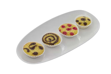 Four small cakes on a plate isolated over whiteの写真素材