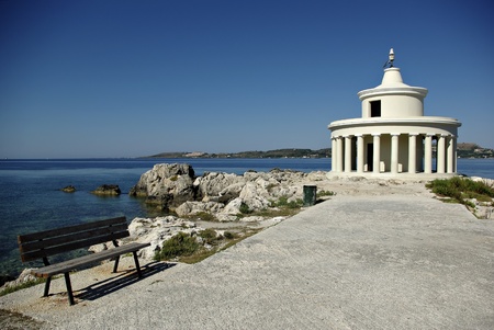 Lighthouse and bench at bay entrance at sunny summer day.の写真素材