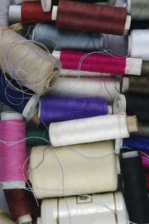 Sewing cotton in different colors, packed and unpacked, in plastic box.