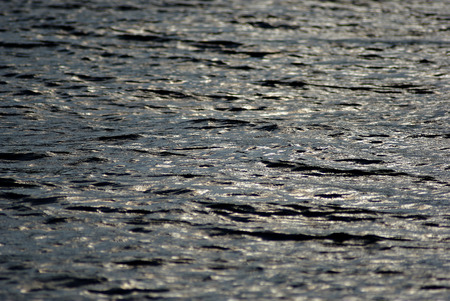 Sea surface with out of focus sun reflections and waves at sunny summer afternoon.の写真素材