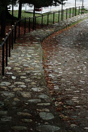 Cobblestone sidewalk and street with metal fence at the old part of the city.の写真素材