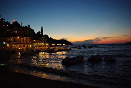 Small seashore town at dusk, harbour with boats, clear blue sky with sunset.の写真素材