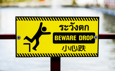 alert  beware drop sign in yellow color have Thailand English and China languageの写真素材