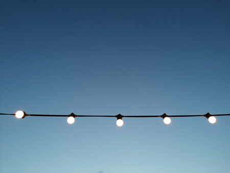 a many light bulb with wire cable in  blue skyの写真素材