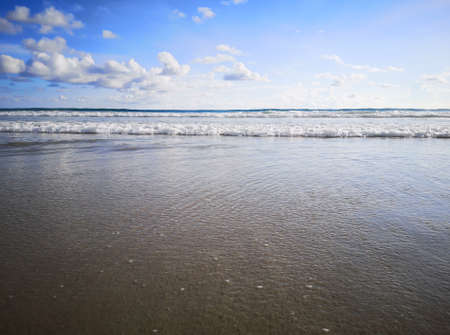 somebody standing on the beach and soft wave crashing on their lags
