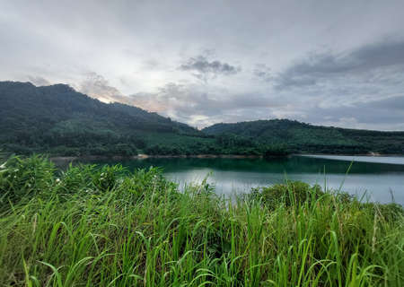 the lake view among the mountains dam with Rain Cloud sky where the sun is going to setの写真素材