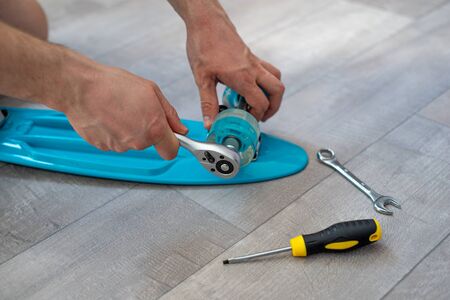 Man fixing blue kid skateboard