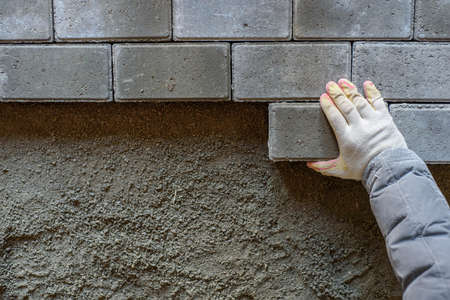 A man's hand is laying the paving stones. Top view