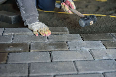 Man laying paving stones on the floor using a rubber mallet