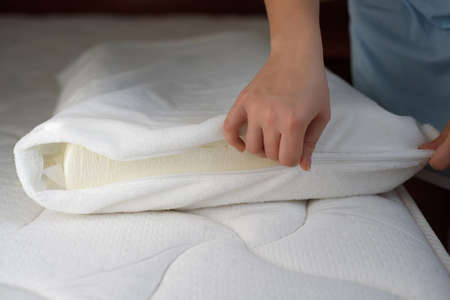 Women's hands put a cover on the orthopedic pillow. Protecting the foam pillow from moisture