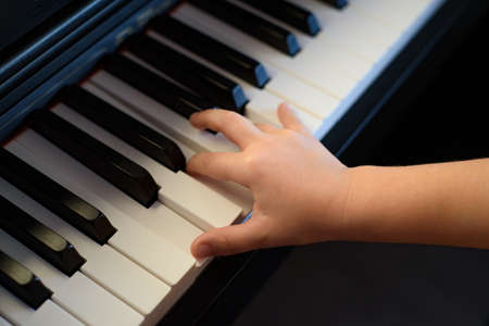 A child's hand presses the piano keys. Early musical development in young childrenの写真素材